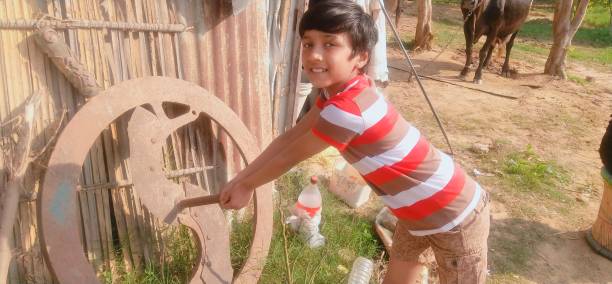 There are wheels of wheeled tractor at close range. In the foreground pre-teen boy has got into the first. He is dozing and basking in the sun.