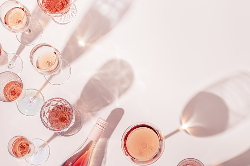 Surtido de vino rosa en copas de cristal, botella de vino espumoso de champán rosa con luz diurna y sombras. photo
