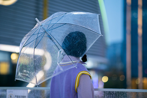 Asian girl walking holding an umbrella in rain day