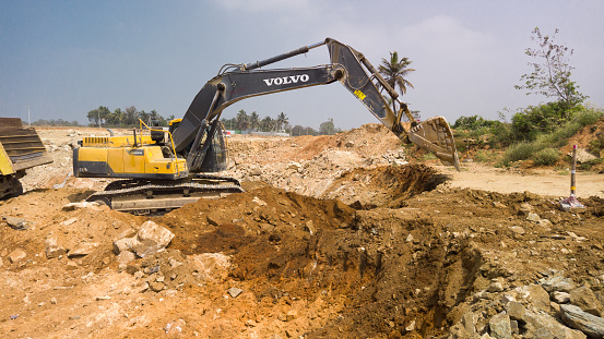 An Heavy Earth moving vehicle is seen in action removing soil at a Civil construction work of a Ten lane Express way near Mysuru in Karnataka,India.