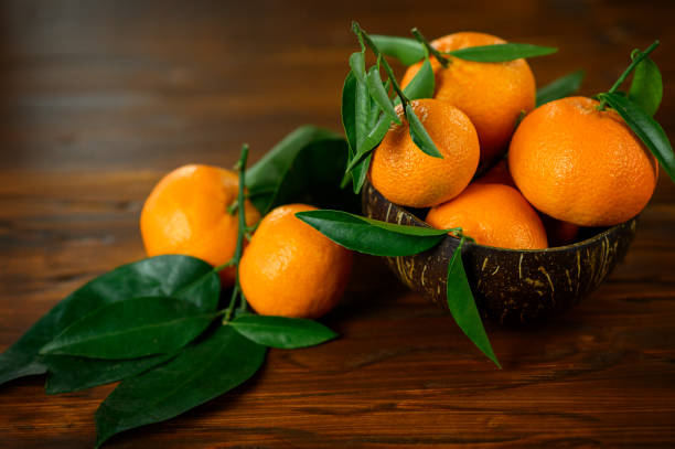 istock Fresh Tangerines With Leaves In Bowl On Wooden Table. 1309682115