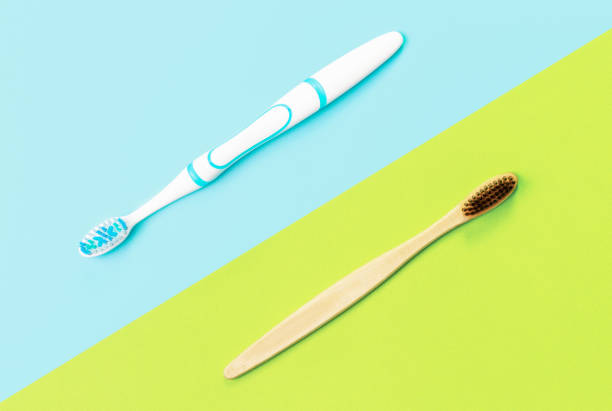 istock Bamboo and plastic toothbrush on blue and green background, top view. 1309683426