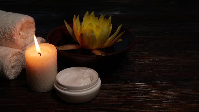 Lotus water lily flower, cream, towels and candle on wooden table