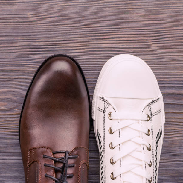zapatos marrones clásicos para hombre y zapatillas blancas sobre un fondo de madera. vista superior - baseball men classic adult fotografías e imágenes de stock