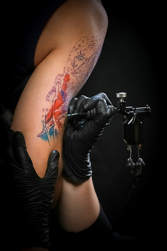 Female tattoo artist making tattoo on a men