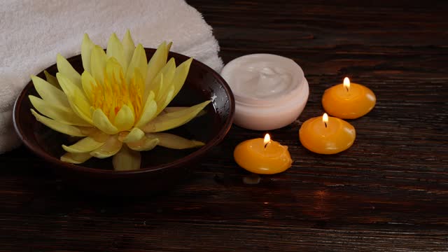 Lotus water lily flower, cream, towels and candles on wooden table