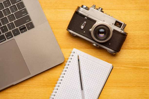 Top view off office photography desk table with laptop, notebook, camera and pen.