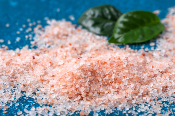 Pink coarse salt crystals on blue table. Himalaya salt. Background for advertising salty. Pink coarse salt crystals on a blue table. Himalaya salt. Background for advertising salty. brackish water stock pictures, royalty-free photos & images