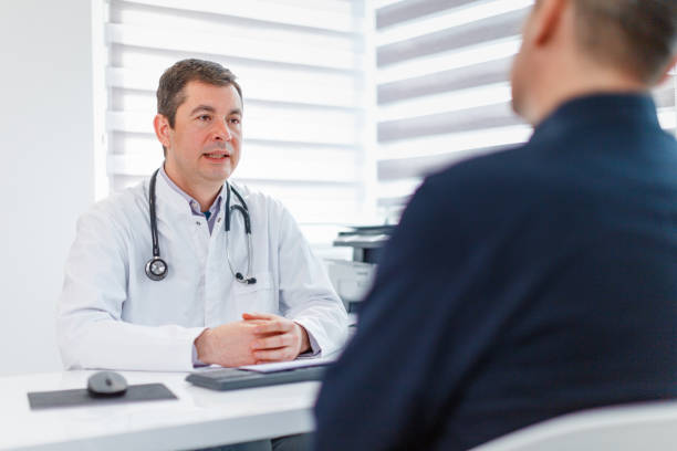 istock Physician sitting at his desk and talking to patient 1309685365