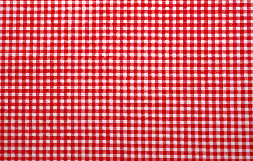 Red and white checkered tablecloth. Top view table cloth texture background. Red gingham pattern fabric. Picnic blanket texture. Red table cloth for Italian food menu. Square pattern of gingham.
