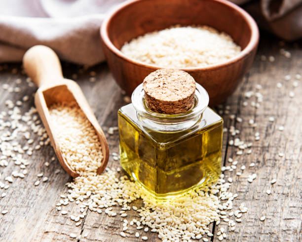 istock Sesame oil and seeds on a rustic table. 1309689687