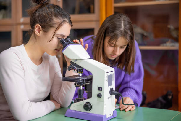 istock High school girls doing project in pair for biology class, using microscope 1309692505