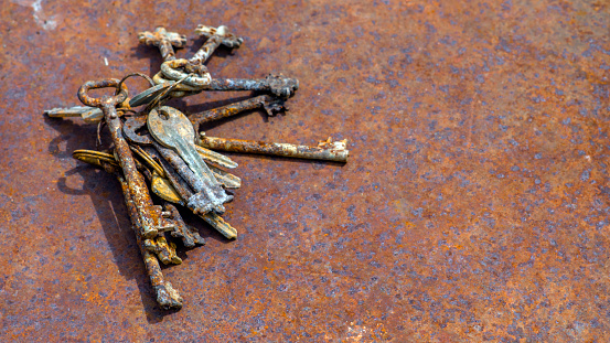 Several old rusty keys on ring shot on steel textured background.