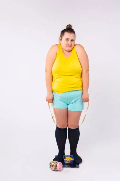 Photo of Body rejection, dissatisfaction concept. Blonde large woman with low self-esteem looking at camera, sitting on scales dissatisfied with her weight. Disgust to self appearance, Mental problem