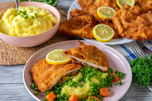 Homemade Pork schnitzel meal served with mashed potatoes and vegetables on a plate. Family meal still life from above view
