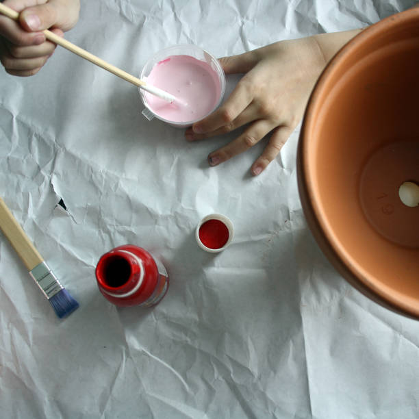 istock A child's hand paints a flower pot pink. 1309695076
