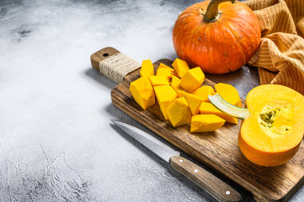 istock Sliced raw orange pumpkin on a chopping Board. White background. Top view. Copy space. 1309697269