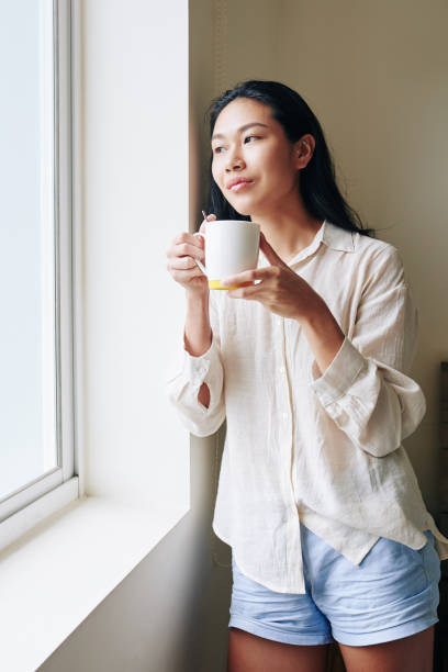 istock Pensive woman standing at window 1309698374