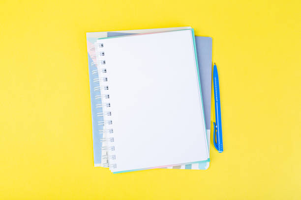 istock open spiral notepad on a yellow background with a pen. top view, stack of notepad with blank sheet. school concept, businessman work desk. 1309699128