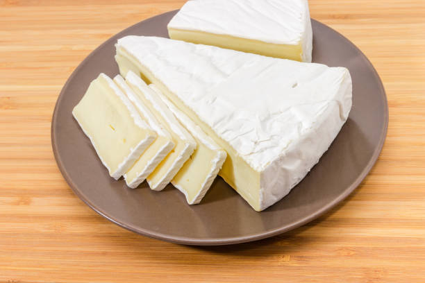 istock Pieces of brie cheese on brown dish on wooden surface 1309700113