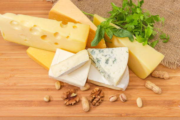 istock Different types cheese with greens and nuts on wooden surface 1309700720