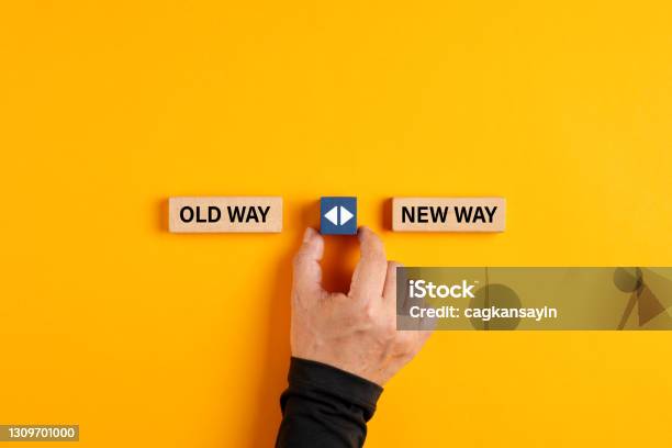 Male Hand Holds A Wooden Cube With Arrow Icon Between The Options Of Old Way Or New Way Stock Photo - Download Image Now