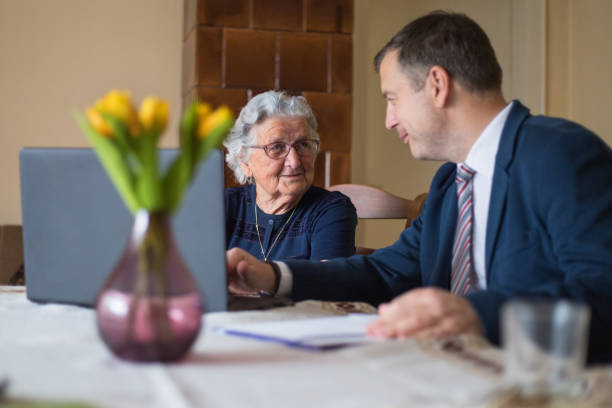 femme plus âgé parlant à l’agent immobilier et utilisant l’ordinateur portatif - lawyer family talking discussion photos et images de collection