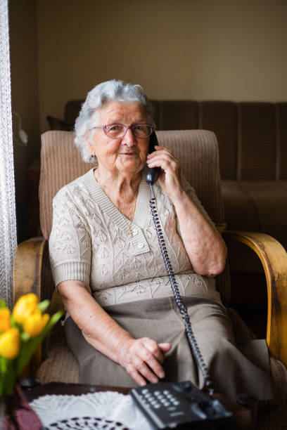 istock Cheerful old woman having phone conversation at home 1309701610