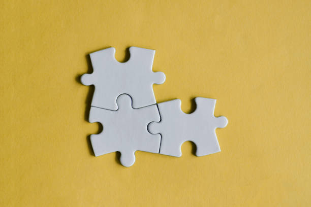 istock Three white jigsaw puzzle pieces on the yellow background. 1309701803