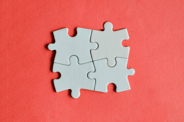 istock Four white jigsaw puzzle pieces on the red background. 1309701849