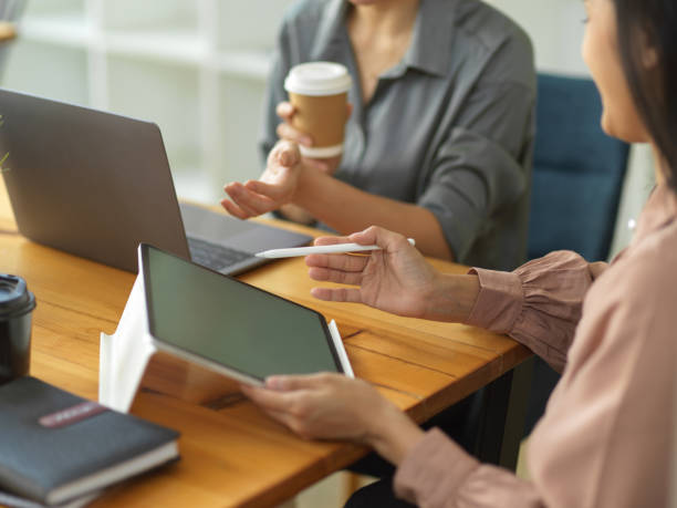 istock Two businesswomen using digital tablet and laptop while sharing idea to each other 1309702537