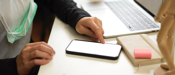 istock Side view of female touching on mock up smartphone screen while working in workplace 1309702632