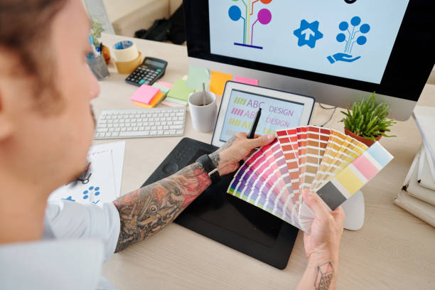 Designer choosing color Hands of graphic designer looking at palette and choosing color for company logog graphic designer stock pictures, royalty-free photos & images