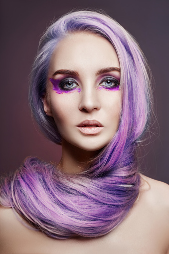 Woman long hair coloring in purple, natural make-up. Stylish hairstyle curls done in a beauty salon. Fashion woman purple color, beauty hair cosmetics and makeup