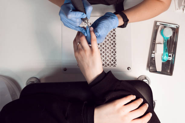 istock A manicurist in a black face mask makes and blue gloves manicure for a client using an electric nail file. Female hardware manicure in the salon. 1309704513