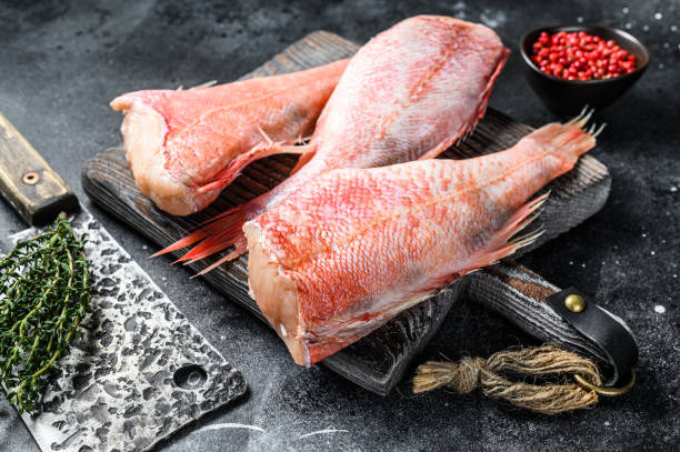 istock Raw Red perch or seabass fish on a cutting board. Black background. Top view 1309704682