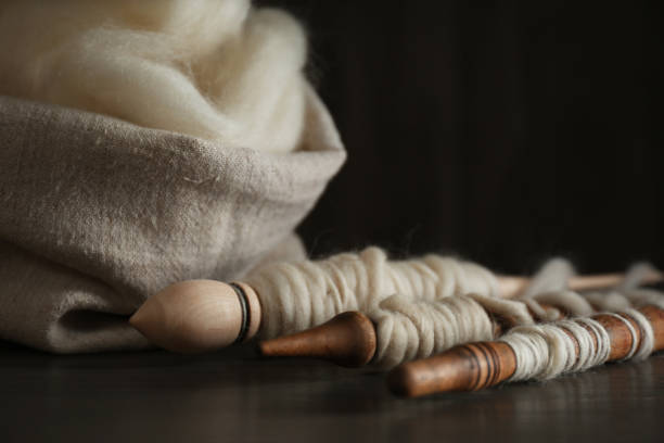 laine blanche douce et fuseaux sur la table en bois, plan rapproché - fuseau photos et images de collection