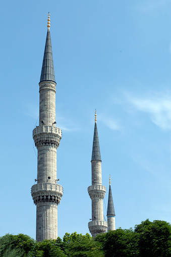 Minaret of Sultan Ahmed Mosque (Blue Mosque) towards the cloudy blue sky in Istanbul.