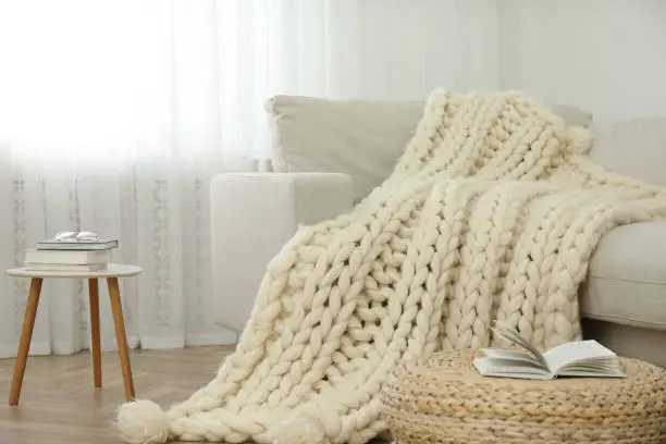 Knitted merino wool plaid on sofa in room