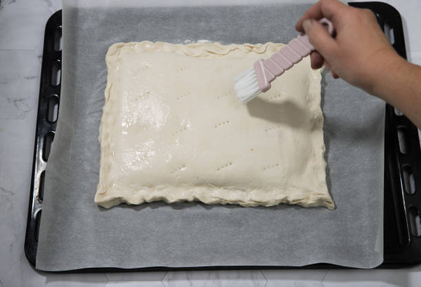 istock A woman's hand greases a homemade pie lying on a baking sheet before baking. Horizontal orientation 1309705745