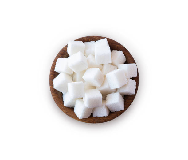 istock Wooden bowl with white sugar cubes. Sugar cube isolated on white. Selective focus. Sugar cube in wooden bowl on white background. Top view. 1309706110