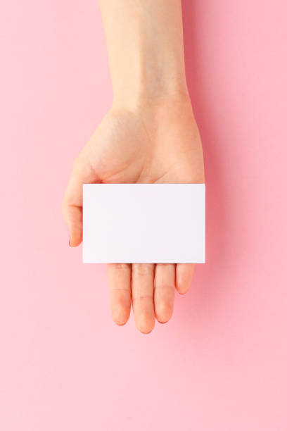 istock Female hand showing empty business card on pink background. Flat lay 1309707376