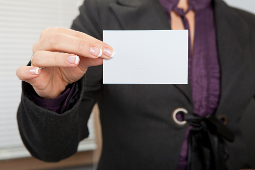 Young business girl in office holding blank card