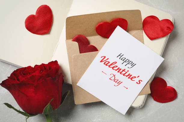 istock Happy Valentine's Day. Composition with greeting card, rose and notebook on light grey marble table, above view 1309709290