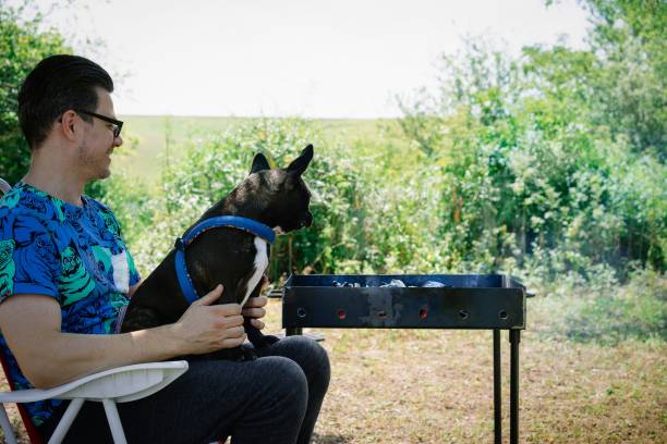 istock Man With Dog Sitting Outdoors By Barbecue Grill 1309709494