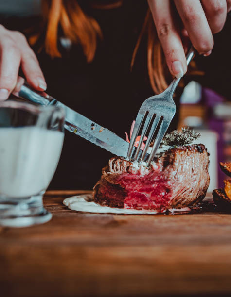 istock woman hands with fork and knife eating beef steak in cafe 1309712881