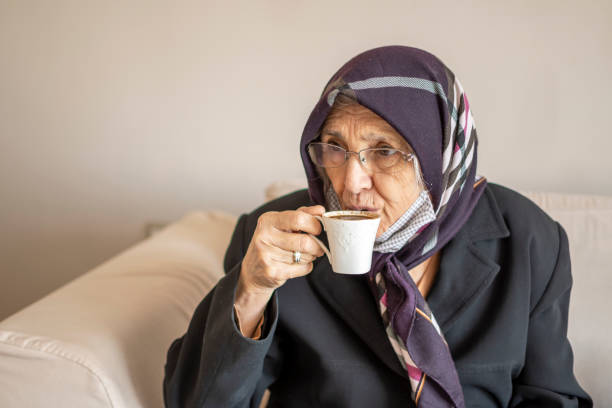 istock Senior woman drinking coffee indoors 1309714720
