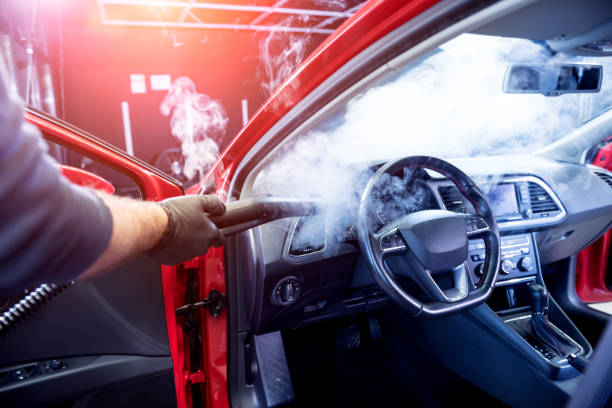 istock Car service worker cleans interiror with steam cleaner 1309716270