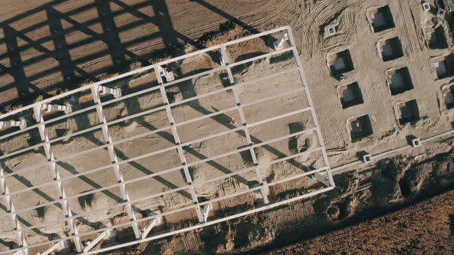 Drone shot of three construction workers looking up at the camera while they evaluating construction progress at the construction site.