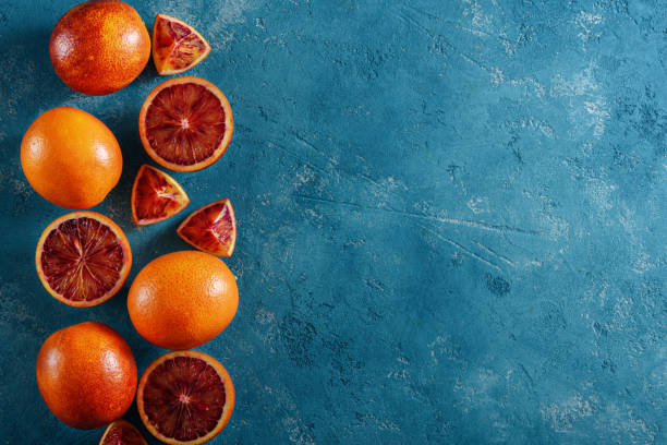 istock red oranges, slices, halves on blue background with copy space, food composition, top view, flat lay 1309719444